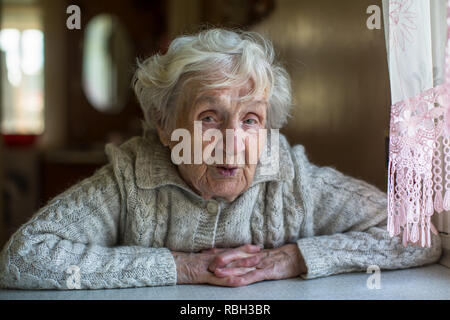 Portrait de personne âgée retraitée dame avec un regard ironique à la table. Banque D'Images