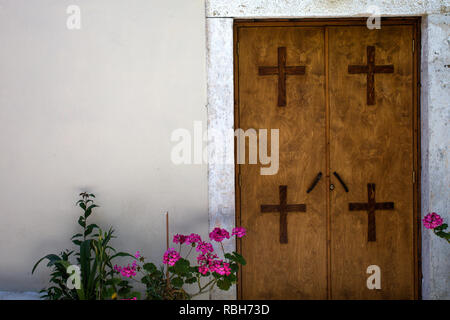 Quatre Croix montée sur deux groupes de porte fermée. Tous les matériaux sont faits de bois contre le mur cimenté blanc. Plantes à fleurs rose placé à l'Entr Banque D'Images