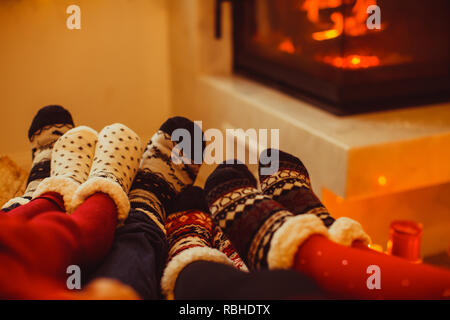 Grande famille se réchauffe près de la cheminée en hiver journée froide. Interieur moderne, l'accent sur les chaussettes Banque D'Images