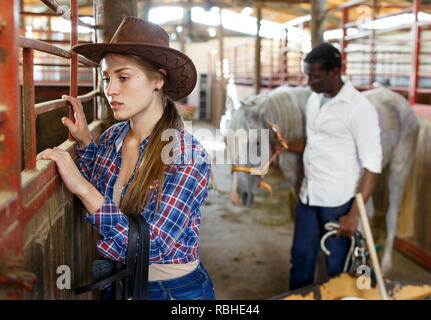 Portrait de jeune fille travailleuse agricole debout à horse stable Banque D'Images