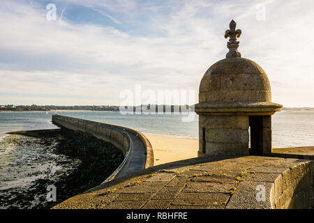 Le brise-lames de la vieille ville de Saint-Malo en Bretagne, vu à marée basse et du coucher du soleil à partir de la muraille de la ville, avec une tourelle de granit à l'avant-plan. Banque D'Images