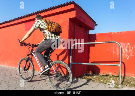 Le contraste des couleurs, un cycliste à cheval autour d'un mur rouge Banque D'Images