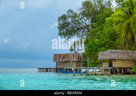 Le rivage d'une petite île de l'Indonésie. Deux bungalows sur pilotis de paille. La végétation tropicale luxuriante Banque D'Images