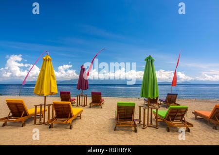 La plage de sable tropicale. Vide transats, parasols de plage fermée et ciel bleu avec des nuages Banque D'Images