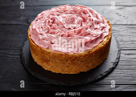 Cheesecake framboise garni de fromage à la crème avec motif couleur framboises sur une pierre noire sur le plateau de table en bois, vue de dessus, close-up Banque D'Images