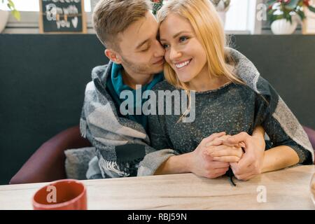 Automne hiver portrait of young couple embracing. Young man and woman in cafe sous couverture de laine chaude boire du café thé, heureux ensemble. Banque D'Images