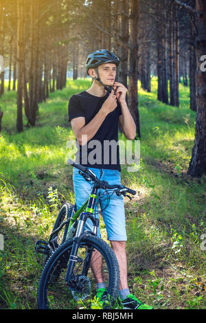 Cycliste homme porte un casque gris sport sur sa tête dans l'arrière-plan de la nature verte. Le concept de protection obligatoire au cours de Vélo Banque D'Images