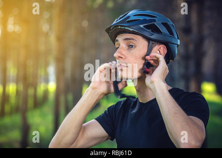 Cycliste homme porte un casque gris sport sur sa tête dans l'arrière-plan de la nature verte. Le concept de protection obligatoire au cours de Vélo Banque D'Images