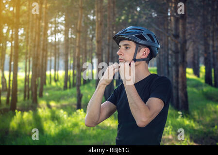 Cycliste homme porte un casque gris sport sur sa tête dans l'arrière-plan de la nature verte. Le concept de protection obligatoire au cours de Vélo Banque D'Images