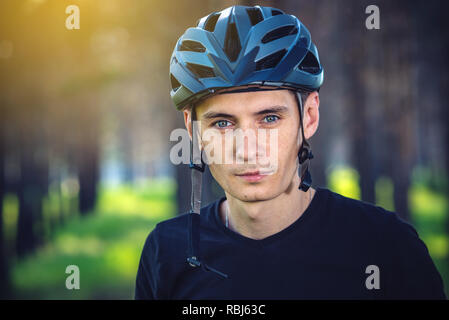 Cycliste homme porte un casque gris sport sur sa tête dans l'arrière-plan de la nature verte. Le concept de protection obligatoire au cours de Vélo Banque D'Images