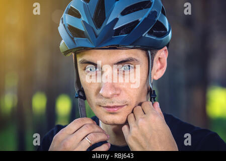 Cycliste homme porte un casque gris sport sur sa tête dans l'arrière-plan de la nature verte. Le concept de protection obligatoire au cours de Vélo Banque D'Images