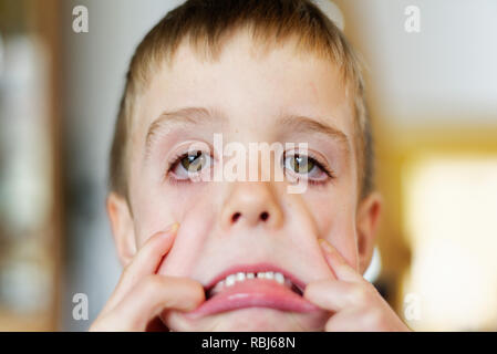 Un jeune garçon (6 ans) pulling faces à l'appareil photo Banque D'Images