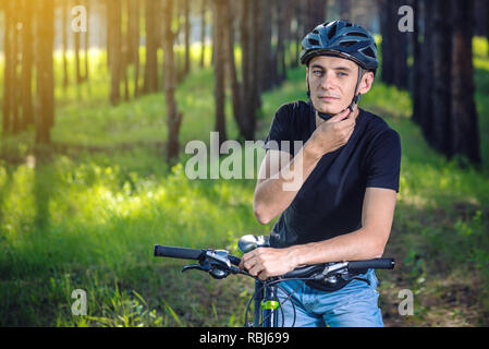 Cycliste homme porte un casque gris sport sur sa tête dans l'arrière-plan de la nature verte. Le concept de protection obligatoire au cours de Vélo Banque D'Images