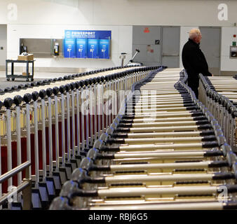 Personnes debout par des rangées de chariots à bagages à l'aéroport Pearson de Toronto en attente de leurs bagages pour arriver. Banque D'Images