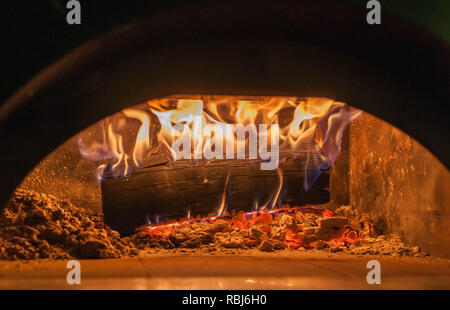 Le bois brûle dans le four à pizza close up sur les flammes et braises brûlantes Banque D'Images
