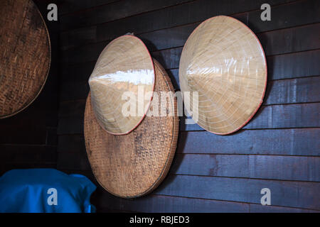 Vintage produits tissés (agriculteur en bois de bambou et chapeaux panier de battage ou bac) accroché sur le mur en bois rustique. L'agriculture, de l'Asie traditionnelle Thai ru Banque D'Images
