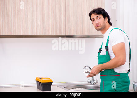 Les jeunes plumber repairing à robinet cuisine Banque D'Images