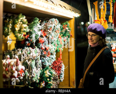 Belle femme française portant béret trendy fashion hat admirant le des couronnes de Noël au traditionnel Marché de Noël annuel à Strasbourg Alsace France Banque D'Images