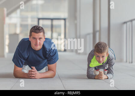 Petit garçon et son farher faisant des pousées exercices ensemble dans un centre sportif. Père et fils passent du temps ensemble et de mener une vie saine.Workin Banque D'Images