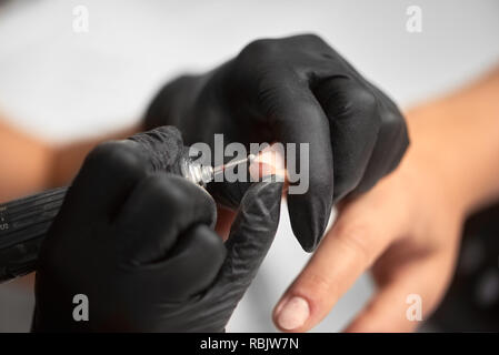 Close-up du maître boucher les mains dans des gants noirs dépose avec cuticule coupe-ongles ongles de client. Traitement professionnel des ongles, t Banque D'Images