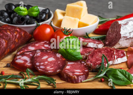 Bac alimentaire avec de délicieux salami, fromage, bacon, saucisses fumées, les olives, les tomates et les herbes. Plateau de viande sur la table en bois. close up Banque D'Images