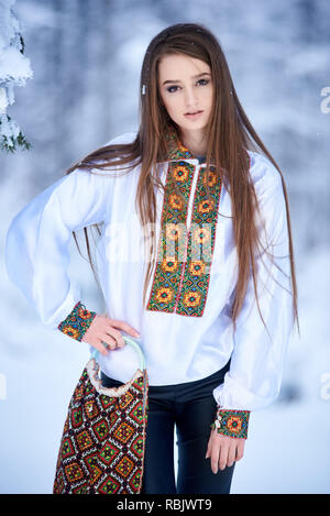 Les jeunes à la mode attrayant de long-haired woman en jeans et chemisier blanc brodé traditionnelle ukrainienne holding , sac avec embroid multicolores Banque D'Images