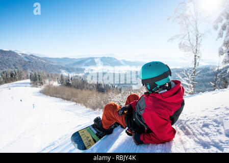 Coquille tiré d'un homme détendu snowboarder allongé sur la pente enneigée bénéficiant de superbes vue montagnes se reposant après équitation à la station de sports d'hiver Loisirs activité vie paysage copyspace Banque D'Images