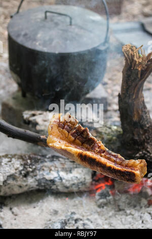 Camping électrique sur la gravure de camp et bacon sur brochette. La cuisine de camp. Cuisson au four hollandais Banque D'Images