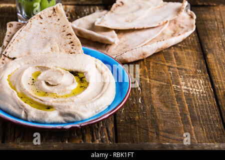 Snack vegan sain, houmous servi avec pain pita et bâtonnets de concombre sur table en bois rustique, Close up, selective focus Banque D'Images