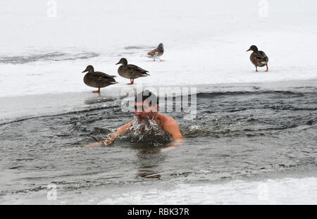 Un homme vu dans un trou dans la glace sur le fleuve Dniepr. Banque D'Images