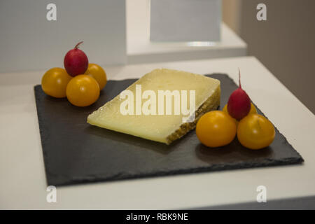 Tranche de fromage de brebis sur nappe noire avec des tomates jaunes et rouges épluchés. Banque D'Images