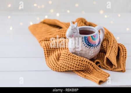 Mug en forme de Lama colorés avec pull tricoté sur la table en bois blanc, teinté Banque D'Images