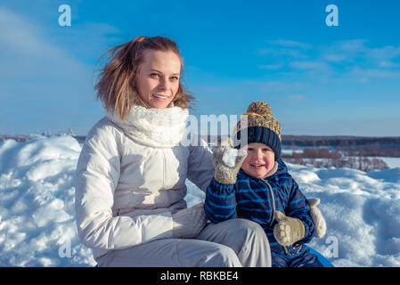 Maman avec le petit fils de 3 ans, en journée ensoleillée dans une ville dans l'hiver. Boules de jouer. Happy smiling se détendre dans la nature. Famille heureuse dans l'air frais. Banque D'Images