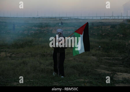 11 janvier 2019 - Gaza, ? ? ? ?  ? ? ? ? ? ? ?/ ? ? ? ?, Palestine - Palestinian demonstrator vu tenant un drapeau palestinien au milieu des gaz lacrymogènes fumigènes autour d'eux pendant la manifestation.palestiniens se sont affrontés avec les forces israéliennes au cours des manifestations sur le mur entre Gaza et Israël à l'est de Khan Yunis. Credit : Yousef Masoud SOPA/Images/ZUMA/Alamy Fil Live News Banque D'Images