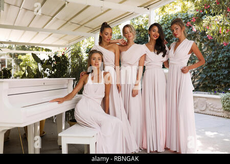 Féminin d'offres à la lumière chers robes rose debout près du piano, terrasse, restaurant , événement, fête, maquillage, coiffure, Mode, beauté Banque D'Images