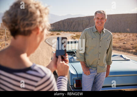 Femme de prendre son mari on road trip with smartphone Banque D'Images