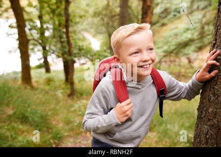 Pré-ado garçon faire une pause en s'appuyant sur un arbre pendant une randonnée dans une forêt, portrait, Close up Banque D'Images
