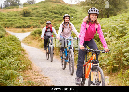 Pre-teen girl riding mountain bike avec ses parents durant un voyage de camping familial, Close up Banque D'Images