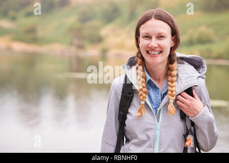 Jeune femme adulte sur un camping appartement de standing by a lake laughing, portrait, Lake District, UK Banque D'Images