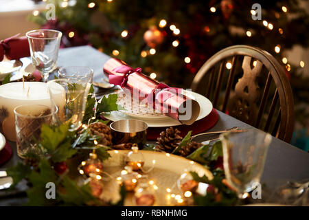 Avec une table de Noël Christmas Cracker disposées sur une plaque avec des décorations de table rouge et vert et un arbre de Noël dans l'arrière-plan Banque D'Images