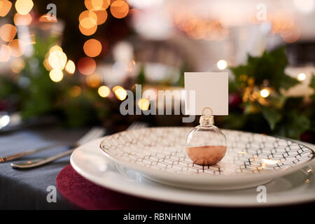 Christmas table setting avec hochet porte-carte nom disposées sur une plaque et les décorations de table rouge et vert Banque D'Images