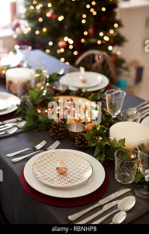 Réglage de la table de Noël avec hochet porte-carte nom disposées sur une plaque et les décorations de table vert et rouge, arbre de Noël en arrière-plan, l'elevated view Banque D'Images