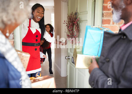 Les grands-parents d'être accueillis par la mère et les enfants qu'ils arrivent pour visiter le Jour de Noël avec des Cadeaux Banque D'Images