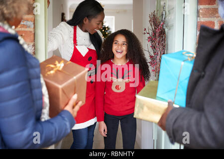 Les grands-parents d'être accueillis par la mère et la fille qu'ils arrivent pour visiter le Jour de Noël avec des Cadeaux Banque D'Images