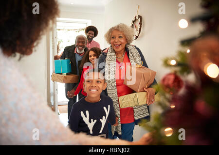 Les grands-parents d'être accueilli par sa famille alors qu'ils arrivent pour visiter le Jour de Noël avec des Cadeaux Banque D'Images
