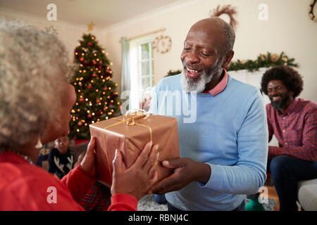 Senior Couple échangeant des cadeaux alors qu'ils célèbrent Noël à la maison avec la famille Banque D'Images