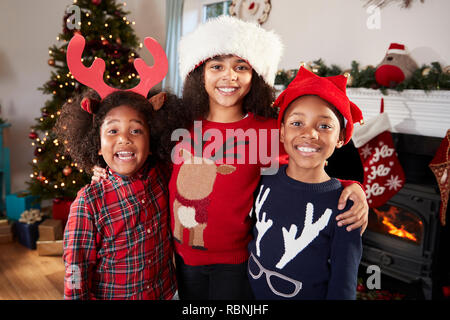 Portrait d'enfants portant des chapeaux de fête des cavaliers et célébrer Noël ensemble, à la maison Banque D'Images