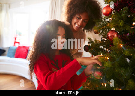 Mère et fille décorations suspendues sur l'arbre de Noël à la maison Banque D'Images