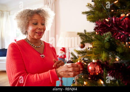 Senior Woman Hanging Décoration de sapin de Noël ensemble, à la maison Banque D'Images