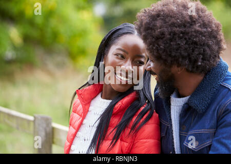 Happy black couple leaning on une clôture dans la campagne se regarder dans les yeux, Close up Banque D'Images